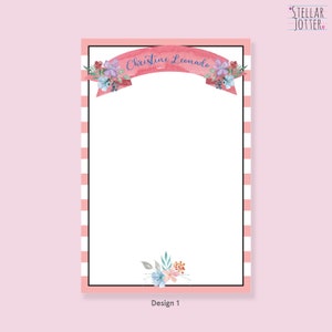 May include: A pink and white striped stationery notepad with a floral design and a banner that says "Christine Leonardo". The notepad is labelled "Design 1".