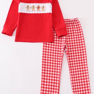May include: Red and white checkered pajama pants with a red long-sleeved shirt featuring a white embroidered gingerbread man design.