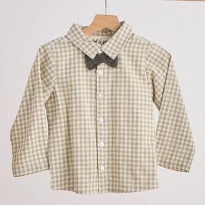 May include: A beige and white gingham button-down shirt with a matching bow tie. The shirt has long sleeves and a collared neckline. The bow tie is tied around the collar.