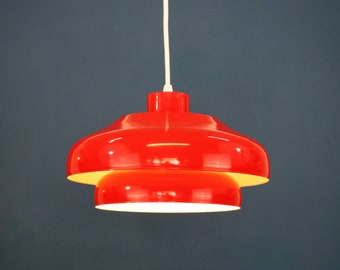 May include: A red pendant light with two tiers. The light is made of metal and has a white cord.
