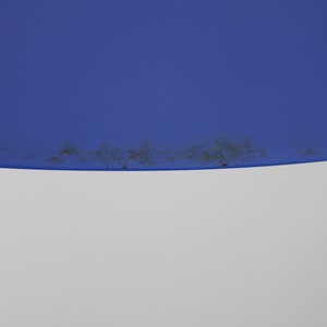 Op de afbeelding: Een close-up van een blauwe en witte lampenkap met een donkerbruine vlek rond de rand.