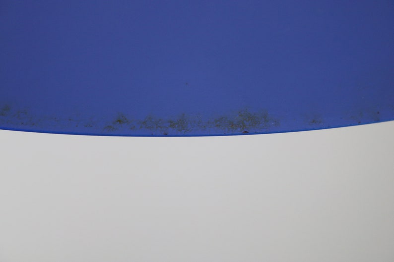 Op de afbeelding: Een close-up van een blauwe en witte lampenkap met een donkerbruine vlek rond de rand.