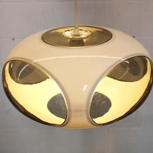 May include: A white and gold pendant light fixture. The light has a rounded shape with a white exterior and gold-colored accents. The light hangs from a white cord.