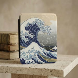 May include: A rectangular case featuring the iconic Japanese artwork "The Great Wave off Kanagawa." The design showcases a large, stylized wave in shades of blue and white, with a glimpse of Mount Fuji in the background. The case has a neutral-toned border.