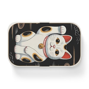 Puede incluir: Gato de la suerte blanco y negro con un collar rojo y una campana, sobre un fondo negro con nubes blancas. El gato está levantando su pata derecha.