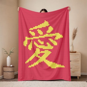 May include: A red blanket with a large yellow pixelated Chinese character. The character is centered on the blanket and appears to be a symbol of love or affection. The blanket is held up by a person.