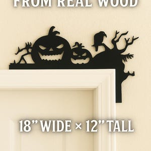 May include: Black wooden Halloween door topper featuring jack-o'-lanterns, a crow, and bare tree branches. The text "HANDCRAFTED FROM REAL WOOD" and "18" WIDE x 12" TALL" are displayed. This decorative piece is designed to sit above a door frame.