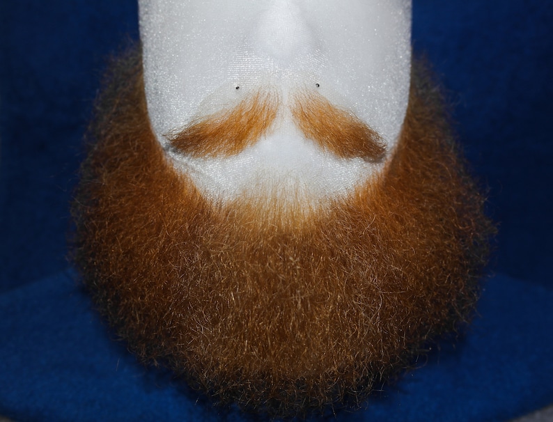 May include: A close-up of a red beard on a mannequin head. The beard is thick and full, with a slight mustache.