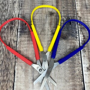 May include: Three pairs of colourful scissors with red, yellow and blue handles. The scissors are made of metal and have a silver finish.