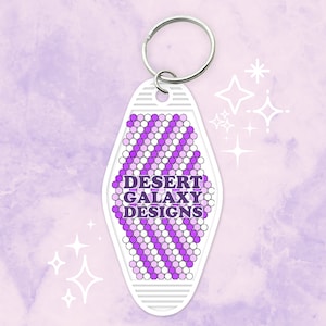 May include: White motel key chain with a purple and white geometric pattern and the text "DESERT GALAXY DESIGNS".