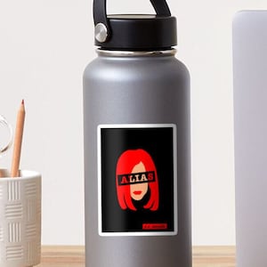 Puede incluir: Una ilustración roja y negra de una mujer con cabello rojo y la palabra "ALIAS" cubriendo sus ojos. El texto "J.J. Abrams" está en la parte inferior de la imagen.