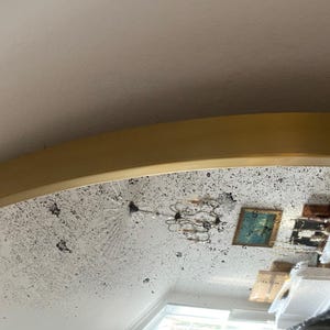 Pode incluir: Um espelho grande, redondo, com moldura dourada e superf&iacute;cie branca desgastada. O espelho reflete uma sala com um candelabro, uma pintura e outros m&oacute;veis.