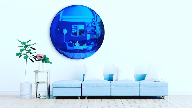 Puede incluir: Un gran espejo de pared convexo, circular y con tinte azul que refleja el interior de una habitaci&oacute;n con un sof&aacute;, estanter&iacute;as y cuadros. El espejo tiene una superficie lisa y reflectante que distorsiona la vista en una perspectiva gran angular.