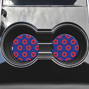 May include: Two blue and red car coasters with a donut pattern. The coasters are in the cup holders of a car.