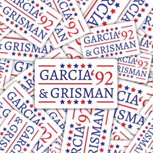 May include: A close-up of a pile of white stickers with red and blue text. The stickers say "Garcia '92 & Grisman" with stars around the text.