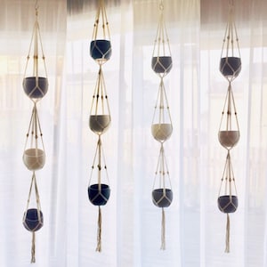 Peut inclure: Quatre suspensions macramées pour plantes, chacune avec trois pots. Les pots sont un mélange de céramique noire et blanche. Les suspensions sont faites de corde de coton naturelle et ont un design simple et minimaliste.