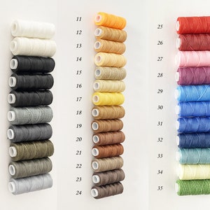 May include: A collection of 35 spools of waxed thread in various colours, numbered 1 through 35. The spools are arranged in three columns.