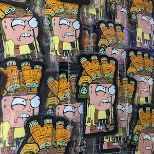 Puede incluir: Primer plano de varios parches de dibujos animados negros y amarillos con un personaje con un gran casco amarillo y una expresión de enfado. Los parches están empaquetados en bolsas de plástico transparentes.