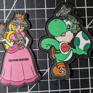 May include: Four embroidered patches featuring characters from the Super Mario Bros. franchise. Mario, Princess Peach, Yoshi, and Luigi are depicted in tactical gear. The Princess patch includes the text "Freedom Fighters".
