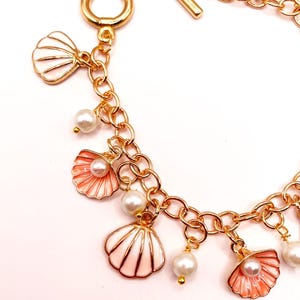 May include: A gold chain bracelet with multiple charms, including pink and white seashells and faux pearls.