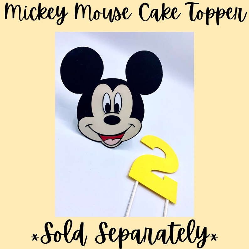 May include: A yellow number two cake topper and a black and white Mickey Mouse head cake topper. The text "Sold Separately" is written below the toppers.