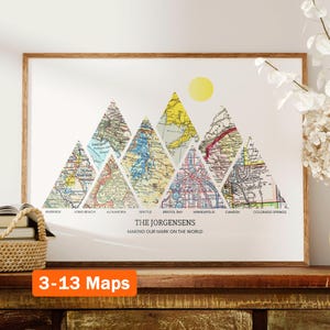 Könnte beinhalten: Ein gerahmter Druck mit einem Bergketten-Design aus Vintage-Karten. Die Berge sind mit Städtenamen wie Riverside, Long Beach, Alexandria, Seattle, Bristol Bay, Minneapolis, Camden und Colorado Springs beschriftet. Der Text "The Jorgensens Making Our Mark On The World" befindet sich unterhalb der Berge. Der Druck befindet sich auf einem Holzregal mit einem Weidenkorb und Büchern.