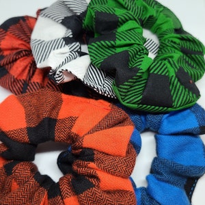 May include: Four scrunchies in different plaid patterns: red and black, green and black, white and black, and blue and black.