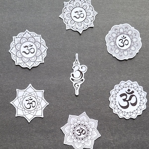 May include: Seven black and white stickers with the Om symbol and intricate mandala designs. The stickers are on a gray background.