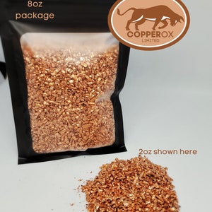 May include: An 8 oz package of copper pieces, with a smaller 2 oz pile of copper pieces shown in the foreground. The package has a black background with the text "8 oz package" and a logo that says "COPPEROX LIMITED".