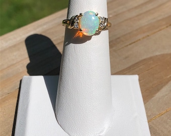May include: A gold ring with an oval opal gemstone and small diamonds set in the band.