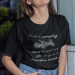 May include: Black t-shirt with white text and motorcycle graphic. The text reads "Power is corrupting. Ideas are what have the power to transform society."