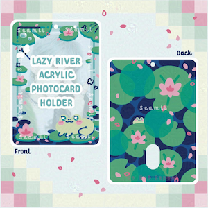 May include: An acrylic photocard holder with a "Lazy River" design. The front has text and a frog illustration, and the back displays a lily pad pattern. The colour scheme includes greens, blues, and pinks.