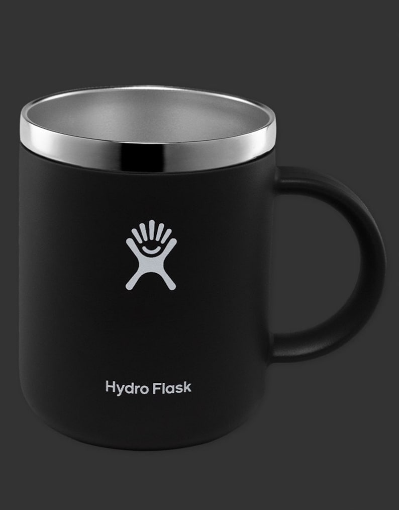 May include: A black Hydro Flask travel mug with a stainless steel lid and a white logo. The mug has a handle and is made of double-walled stainless steel.