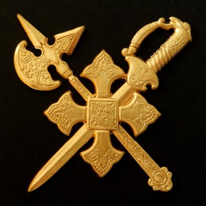 May include: A gold-colored metal cross with a sword, axe, and spear design. The cross is decorated with intricate floral patterns.