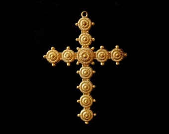 May include: A gold-colored cross pendant with a decorative design of concentric circles. The cross is made of metal and has a loop at the top for hanging.