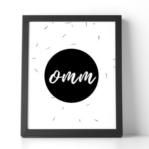 May include: A framed art print with a black frame. The print features a black circle with the word "omm" in white script. The background is white with small black lines radiating from the circle.