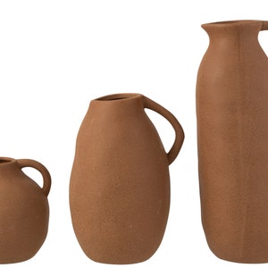 Può includere: Tre vasi in ceramica terracotta con manici. I vasi sono di diverse dimensioni e forme, con una finitura macchiettata.