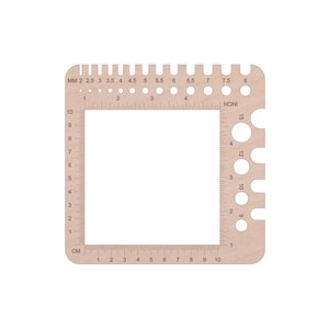 May include: A wooden gauge with a ruler on two sides, marked in centimeters and millimeters. The gauge has a series of holes on one side, labeled with numbers from 1 to 15. HONI is printed on the gauge.