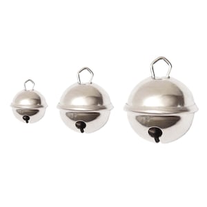 Può includere: Tre campanelle d'argento di diverse dimensioni. Le campanelle sono rotonde e hanno un piccolo anello in cima.