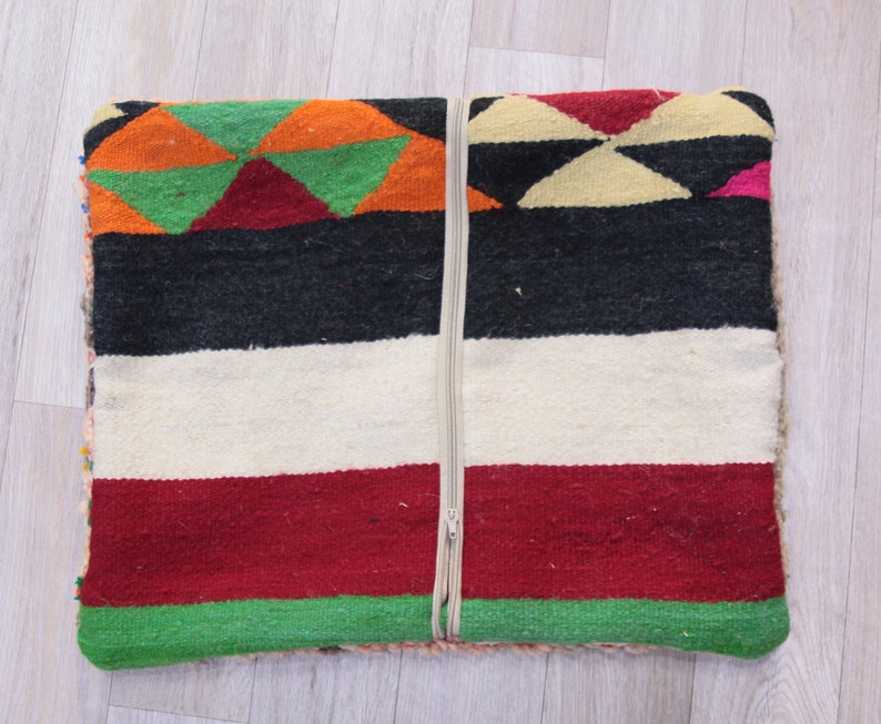 Pu&ograve; includere: Un cuscino tessuto colorato con una chiusura a cerniera. Il cuscino presenta un motivo geometrico in tonalit&agrave; di rosso, verde, arancione, nero e bianco.