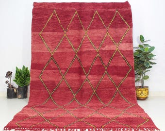 May include: A red Moroccan rug with a diamond pattern in gold and black. The rug has a fringe border.