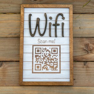 May include: A white wooden sign with a brown frame, the words "Wifi Scan me!" and a black and white QR code.