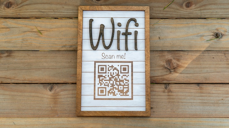 May include: A white wooden sign with a brown frame, the words "Wifi Scan me!" and a black and white QR code.