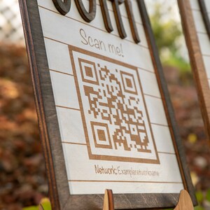 May include: Two wooden signs with a white background and brown trim. Each sign has a QR code with the text "Scan me!" and the words "Wifi" and "Join" in a decorative font.