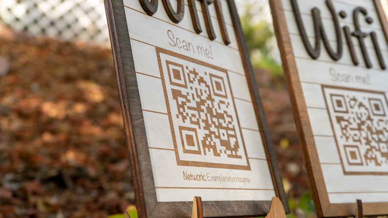 May include: Two wooden signs with a white background and brown trim. Each sign has a QR code with the text "Scan me!" and the words "Wifi" and "Join" in a decorative font.