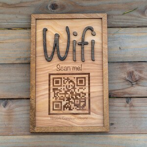 May include: A wooden sign with the word "Wifi" and a QR code that says "Scan me!" The sign is on a wooden background.