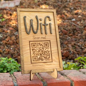 May include: A wooden sign with the word "Wifi" and a QR code that says "Scan me!" The sign is on a small wooden stand.