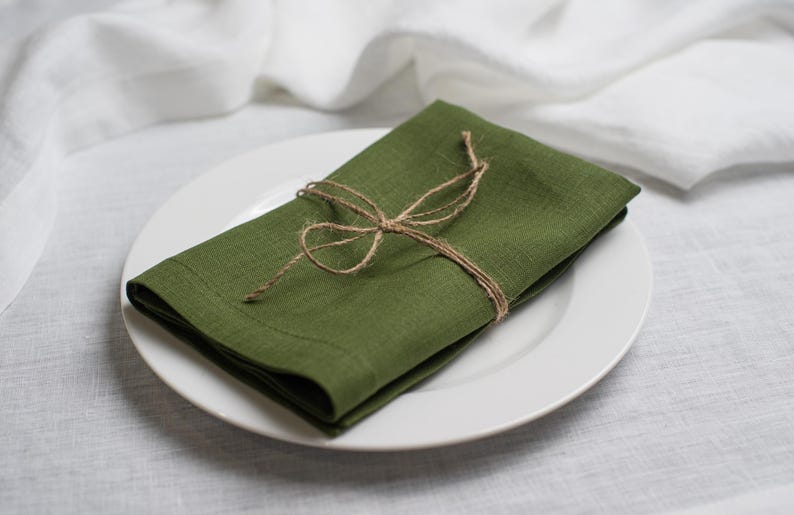 Forest green linen napkin folded and tied with rustic natural twine, beautifully styled on a white ceramic plate. Elegant organic linen table textile designed for sustainable dining, modern table decor, intimate dinners, wedding receptions, farmhouse interiors and seasonal entertaining. Soft washed linen with a rich natural texture, reusable eco friendly cloth napkin for everyday meals, cottagecore styling, luxury tablescapes, holiday gatherings and timeless handmade home decor.