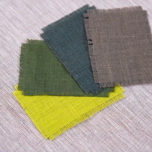 May include: Five fabric swatches in different colors, including brown, green, teal, gray, and yellow. The swatches are arranged in a fan shape and have a rough, textured surface.