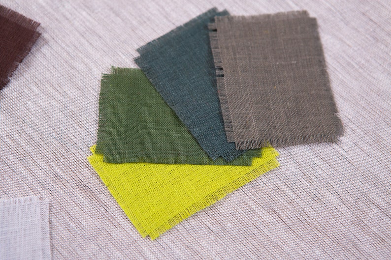 May include: Five fabric swatches in different colors, including brown, green, teal, gray, and yellow. The swatches are arranged in a fan shape and have a rough, textured surface.